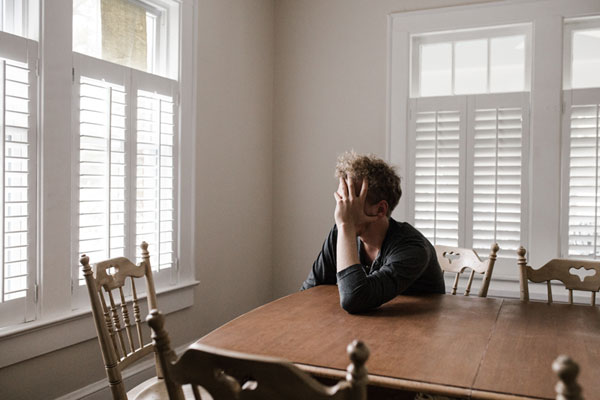 Man leaning on a table, holding his head 