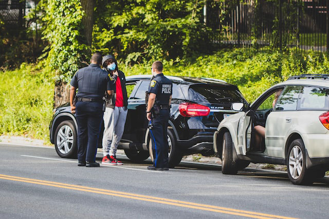 Police officers talking with a man on the road.